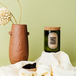 A round, tall green glass candle with a Mexican oak and smoked cacao soy wax scent.
