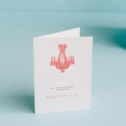 A pink chandelier-style illustration on a white greeting card with the text "Your future is bright" and "Happy birthday to you!"
The image shows a pink, ornate chandelier-style illustration on a white greeting card. The text on the card reads "Your future is bright" and "Happy birthday to you!". This greeting card appears to be for a birthday celebration, with the pink chandelier design and the birthday message.