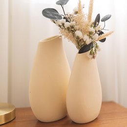Tall, round, off-white ceramic vases with dried floral arrangements. Available in small and large sizes.