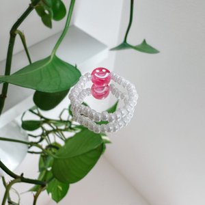 Parelring gemaakt van witte glaskralen met een roze smiley