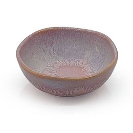A round, shallow stoneware bowl in a soft pink color with a textured, glazed surface.