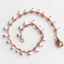 A delicate rose gold-toned bracelet with small white beads arranged in a spiral pattern. The bracelet has an adjustable length and a clasp closure, making it suitable for a variety of wrist sizes.