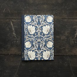 A dark blue notebook with a floral pattern featuring large white flowers and leaves in a repeating design. The notebook appears to be made of high-quality materials and has a classic, elegant style.