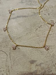 Delicate gold-toned necklace with rose quartz beads, perfect for adding a touch of elegance to any outfit.