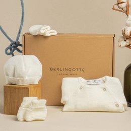 A white, soft, and plush keychain in a baby clothing box. The keychain appears to be made of a cotton or similar soft material, suitable for a baby or young child.