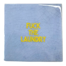  A green tile with the text "LET THEM SMELL A POOPIE" in bold pink letters. The tile appears to be a decorative or humorous home accessory.