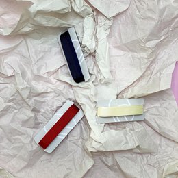 Kaizen Ribbon Set, a collection of colorful ribbons for wrapping gifts and decorating. The ribbons come in various colors including red, white, and black, and have a shiny, satin-like texture.