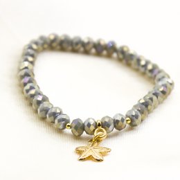 This shiny green and gray bracelet features a delicate charm in the shape of a flower. The bracelet is made of beads that have a faceted, sparkling appearance, adding a touch of elegance to the piece.