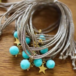 Taupe and gold anklet with turquoise beads and star charms. Boho-inspired design with natural materials.
