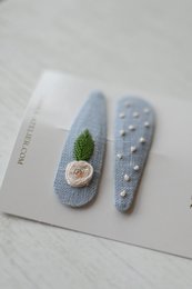 Blue hair clips with rose leaf and dot designs, suitable for casual or formal wear.