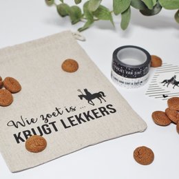  A beige cotton drawstring bag with the text "Who is sweet gets goodies | gingerbread bag" printed on it. The bag contains gingerbread cookies and a small black and white label.