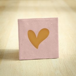A pink square tile with a large golden heart shape in the center. This decorative tile would make a lovely addition to a wall or shelf, conveying a message of love and affection.