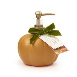 Hand soap dispenser in the shape of a pumpkin with a green ribbon and label. The dispenser is made of a golden-colored material and has a pump mechanism on top.