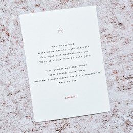 A white greeting card with a handwritten message expressing well wishes for a new home or property.
