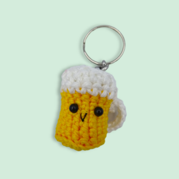 Crocheted beer mug keychain in a bright yellow color with a cute, smiling face.