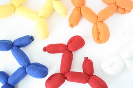 Colorful plush balloon dog toys in various colors including white, pink, blue, orange, yellow, red, dark blue, ochre, petrol, green, purple, and seagreen.
