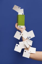 A set of PANTONE sticky note pads in various colors including yellow, blue, light pink, red, green, and grey. The pads are stacked and arranged on a blue background, with some notes floating in the air.