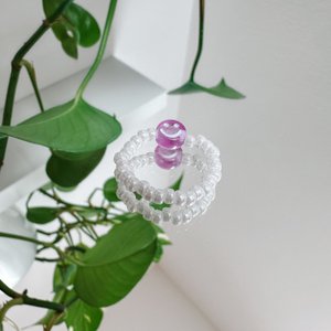 Parelring gemaakt van witte glaskralen met een paarse smiley