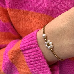 A delicate bracelet featuring a pearl flower design with stainless steel beads in a gold tone. The bracelet has a feminine and elegant style.
