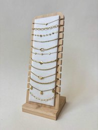 Tall wooden jewelry display stand with multiple white card tiers, showcasing delicate gold and silver chain necklaces.