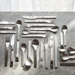 Stainless steel cutlery set with polished, brushed, and matte finishes. Includes forks, knives, and spoons in a variety of shapes and sizes suitable for a place setting.