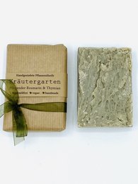 Herb-infused soap bars in a natural, earthy packaging. Features a variety of herbs and a green, textured appearance.