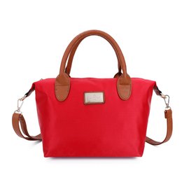  A red crossbody bag with brown leather handles and trim. The bag has a rectangular shape and appears to be made of a durable fabric material. It has a zippered main compartment and an adjustable shoulder strap for versatile carrying.