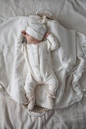 Soft, cozy ivory merino wool baby slippers with delicate ruffles and a woven basket design.