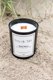 Tall, round, scented candle with a sunlit shores fragrance. Made of wax with a floral design on the container.