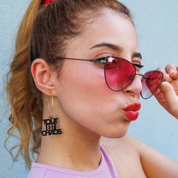 Red heart-shaped sunglasses, mismatched gold hoop earrings, statement accessories, bold fashion style.