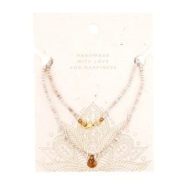 This bronze pendant necklace features a beaded chain with a bronze pendant. The necklace has a natural, earthy style with a simple and elegant design.