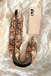 Floral print cross-body bag with adjustable strap in pink and green tones.