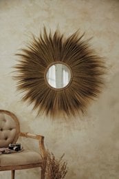 Round, natural-looking mirror with a starburst frame made of brown feathers. Available in natural, beige, bronze, and magenta color variants.
