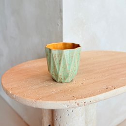 Small stoneware cup with a spring glow design featuring a geometric pattern in green and orange colors.