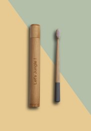 Bamboo toothbrush with travel case in black, grey, and white colors. Eco-friendly oral care product.