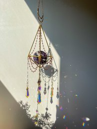 Amethyst-colored suncatcher sphere with hanging beads and charms, creating a dreamcatcher-inspired design.