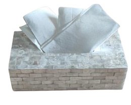 A rectangular white tissue box made of a soft, absorbent material, likely paper or fabric, sitting on a stone or concrete surface.