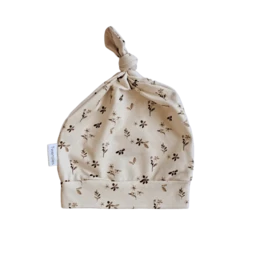 Cream-colored baby cap with small floral print pattern. Suitable for infants aged 0-6 months.