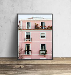 A vibrant pink building with balconies and windows, showcasing a whimsical cat poster.