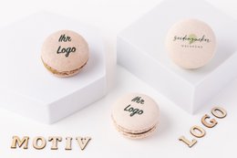 Individually printed macarons in assorted pastel colors, featuring custom logos or text. Delicate, round confections with a soft, chewy texture.