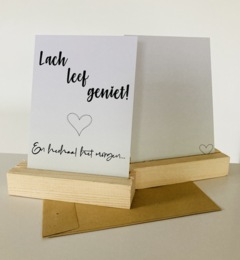 A greeting card with the text "Lach leg genug!" (Laugh enough!) and a heart symbol. The card has a simple, minimalist design with a white background and black text.