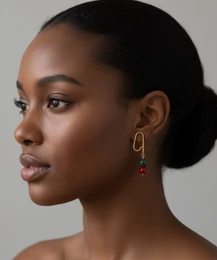 Gold oval hoop earrings with red beaded drops, statement style, elegant dangle design.