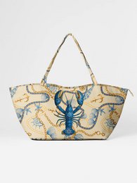 A large floral print weekend bag with a pink gemstone accent. The bag features a variety of colorful flowers including yellow, pink, and purple blooms. The bag has two handles and appears to be made of a durable fabric.