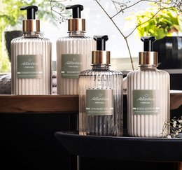 Clear glass bottles with gold pump dispenser, ribbed texture, sage jasmine tonka orange cedarwood scents, luxury bath gel.
