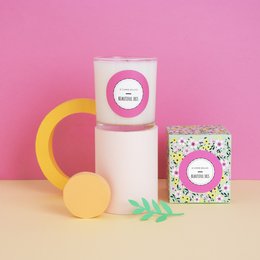Tall, round, scented candle in a white container with a purple label. The candle has a floral, iris scent.