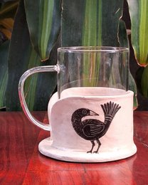 "White ceramic mug with black bird silhouette design, papier-mache holder set, decorative kitchen"