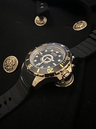 Gold-tone stainless steel watch with black dial and rubber strap. Features a large 55mm case size and water resistance up to 100m.