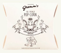 Caramel popcorn coated in white chocolate and spices, 30g pack. Sweet and savory snack.