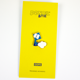 A soft enamel pin in the shape of a pencil with a cloud-like shape, in a bright yellow packaging. The pin appears to be a product from the brand Pencil & Tie, which is described as stationery for creative people, made in the Netherlands.