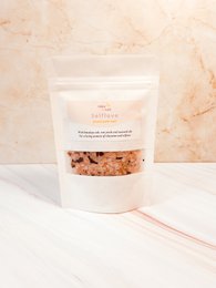 Badzout Zelfliefde is a bath salt product featuring pink Himalayan salt crystals. The product has a natural, earthy appearance with a mix of pink and white salt crystals.